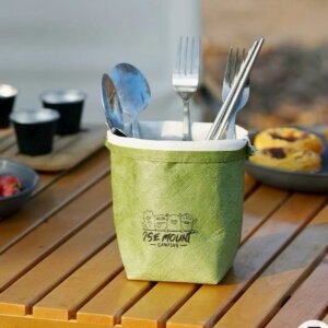 A Green Water-proof Kraft Paper Storage Organizer Holding Utensils on a Camping Table