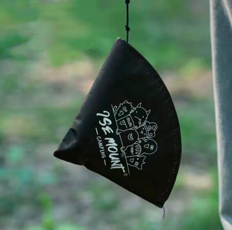 A hanging coffee filter holder attached to a camping setup